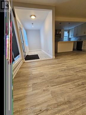 Toronto (Clairlea-Birchmount) apartment for rent - A room with a wooden floor and a kitchen area in the background.