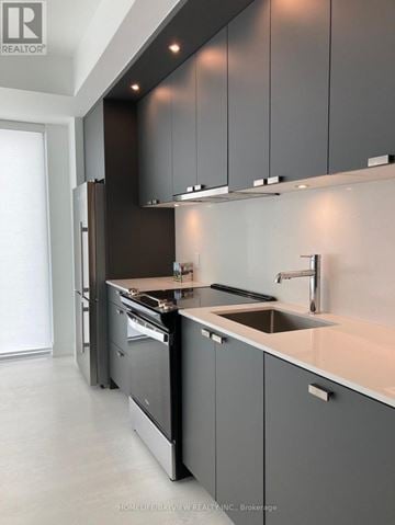 Toronto (Banbury-Don Mills) condo for rent - A modern kitchen with dark grey cabinets and a white countertop.