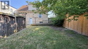Sarnia apartment for rent - A backyard with a fence and a house in the background.