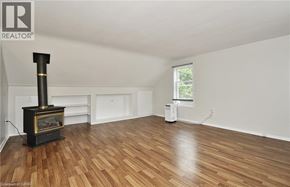 Cambridge apartment for rent - A wood burning stove is in the corner of a large empty room with hardwood floors.