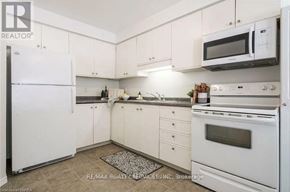 Brantford townhouse for rent - A white kitchen with a refrigerator, microwave, oven, and sink.