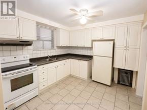 Toronto (Oakwood Village) multi-family for rent - A kitchen with white cabinets and a black countertop.