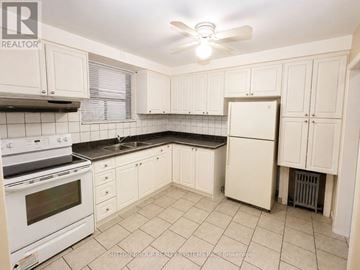 Toronto (Oakwood Village) multi-family for rent - A kitchen with white cabinets and a black countertop.