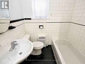 Toronto (Oakwood Village) multi-family for rent - A white sink is on the left of a white toilet in a white tiled bathroom.