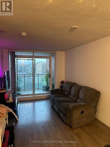 Markham (Commerce Valley) condo for rent - A living room with a grey couch and a sliding glass door.