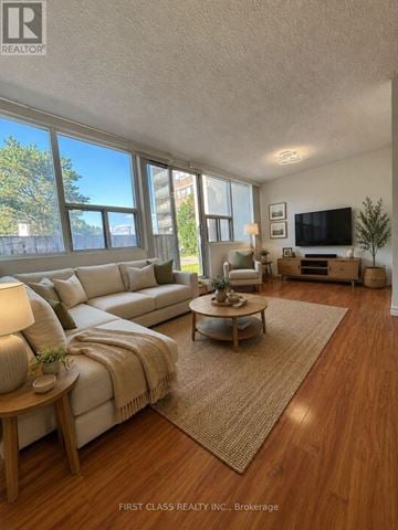 Mississauga (Sheridan) condo for rent - A well-lit living room with a large couch and a flat-screen TV.