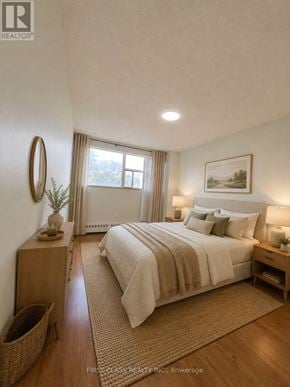 Mississauga (Sheridan) condo for rent - A bedroom with a large bed, a wooden nightstand, and a wicker basket on the floor.
