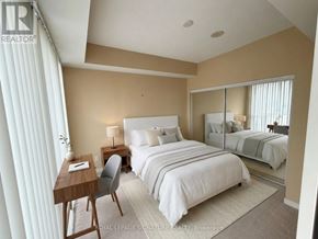 Toronto (Waterfront Communities) condo for rent - A bedroom with a large bed, a desk with a chair, and a mirror on the wall.
