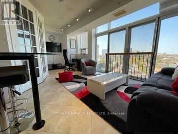 Mississauga (Mississauga Valleys) condo for rent - A living room with a black couch and a red ottoman.