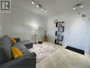 Mississauga (Mississauga Valleys) condo for rent - A living room with a grey couch, a guitar, and a clock on the wall.
