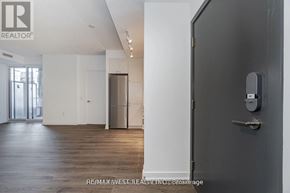 Toronto (Niagara) condo for rent - A modern, empty room with a door and a refrigerator.