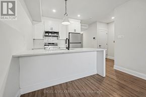 Ottawa multi-family for rent - A white kitchen with a refrigerator, stove, and oven.