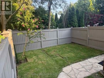 Toronto (Yonge-Eglinton) apartment for rent - A backyard with a fence and a small tree with pink flowers.