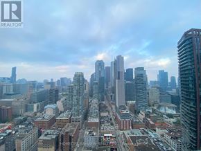 Toronto (Waterfront Communities) condo for rent - A cityscape with a mix of modern and older buildings under a cloudy sky.