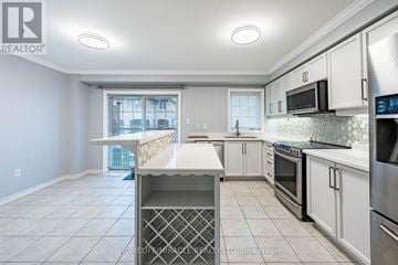 Ajax (Central East) townhouse for rent - A kitchen with white cabinets and appliances, and a large island in the middle.