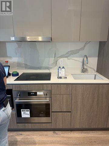 Vaughan (Vaughan Corporate Centre) condo for rent - A person is standing in a kitchen with a sink and a stove.