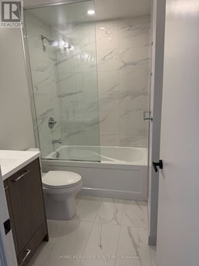 Vaughan (Vaughan Corporate Centre) condo for rent - A bathroom with a glass shower door and a white toilet.