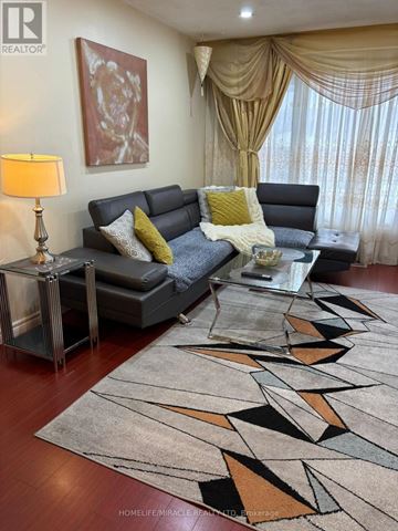 Mississauga (Malton) apartment for rent - A living room with a grey couch, a yellow lamp, and a large abstract painting on the wall.