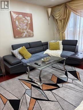 Mississauga (Malton) apartment for rent - A living room with a grey couch, a coffee table, and a rug with a geometric pattern.
