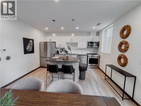 Kitchener condo for rent - A modern kitchen with white cabinets and a wooden island.