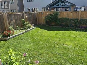 Niagara Falls (Brown) apartment for rent - A backyard with a wooden fence and a green lawn.