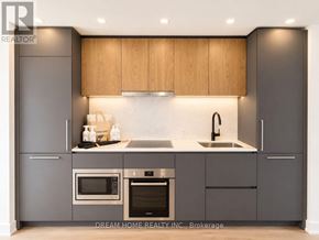 Toronto (North St. James Town) condo for rent - A modern kitchen with wooden cabinets and stainless steel appliances.