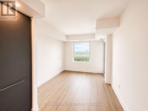 Toronto (North St. James Town) condo for rent - A room with a wooden floor and white walls, with a window showing a view of a cityscape.