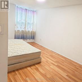 Toronto (West Hill) condo for rent - A bed with a mattress in a room with wooden flooring.