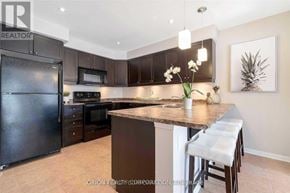 Milton (Wi Willmott) townhouse for rent - A kitchen with a black refrigerator and brown cabinets.