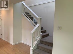 Vancouver apartment for rent - A staircase with a white railing and beige carpeted steps.