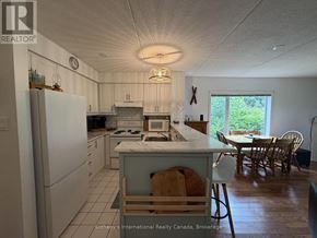 Collingwood townhouse for rent - A kitchen with a white fridge and a white island with a wooden chair.