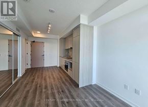 Vaughan (Vaughan Corporate Centre) condo for rent - A spacious room with wooden flooring and white walls, featuring a kitchenette with a sink and cabinets.