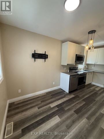 St. Catharines (Facer) apartment for rent - A kitchen with white cabinets and a wooden floor.