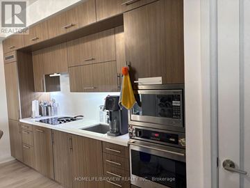 Toronto (Willowdale East) condo for rent - A modern kitchen with wooden cabinets and stainless steel appliances.