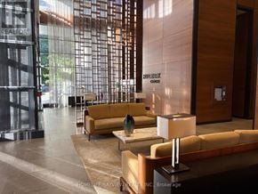 Toronto (Willowdale East) condo for rent - A modern waiting area with a glass wall and a brown sofa.