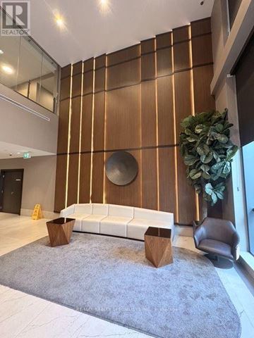 Mississauga (Hurontario) condo for rent - A modern living room with a white sofa and a wooden wall panel.