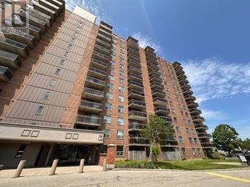 Mississauga (Lakeview) multi-family for rent - A tall apartment building with a parking lot in front.