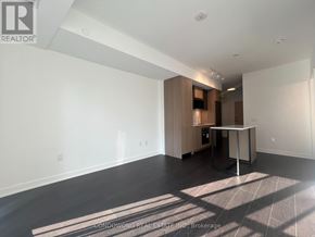 Toronto (Regent Park) condo for rent - A spacious, empty room with a kitchenette in the corner.