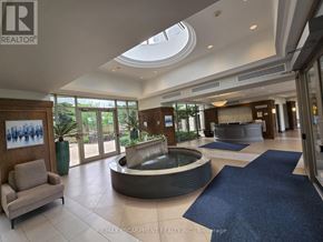 Oakville (Ro River Oaks) condo for rent - A large, well-lit lobby with a fountain and a blue rug.