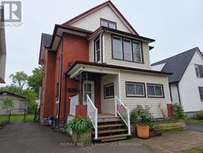 Welland (Welland Downtown) triplex for rent - A two-story house with a red and beige exterior and a white front porch.