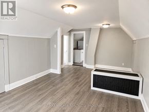Welland (Welland Downtown) triplex for rent - A spacious room with a wood floor and a wall-mounted air conditioner.