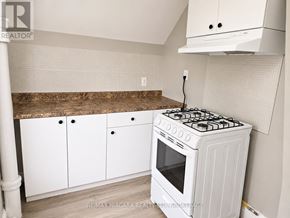 Welland (Welland Downtown) triplex for rent - A white gas stove in a kitchen with white cabinets and a brown countertop.
