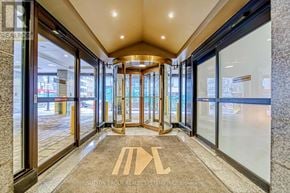 Toronto (Bay Street Corridor) condo for rent - The image shows a hallway with a carpeted floor and a logo on it, leading to a set of glass doors.
