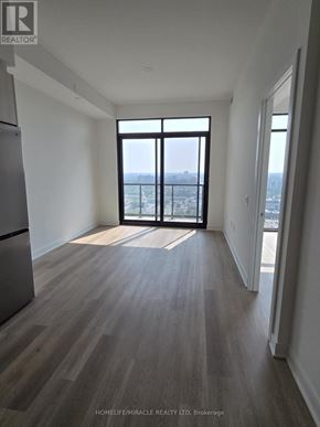 Mississauga (Cooksville) condo for rent - A spacious room with wooden flooring and a large window overlooking the city.