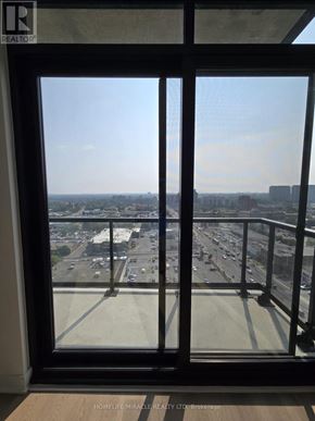 Mississauga (Cooksville) condo for rent - A view from a window looking out at a parking lot and buildings.