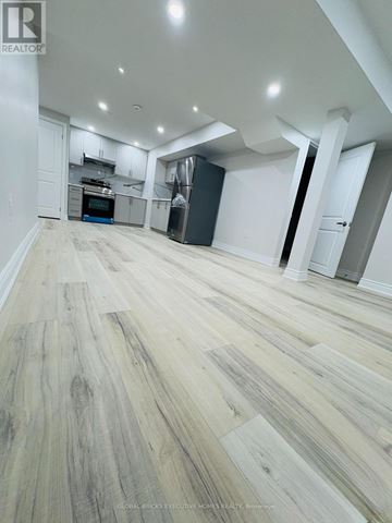 Oakville (Go Glenorchy) apartment for rent - A spacious room with wooden flooring and white walls.