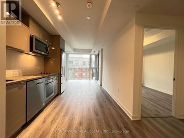 Toronto (Waterfront Communities) condo for rent - A spacious kitchen with wooden floors and a view of the city through the window.