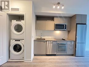 Toronto (Waterfront Communities) condo for rent - A modern kitchen with a washer and dryer built into the cabinetry.