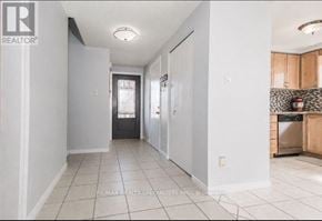Cambridge apartment for rent - A white tiled kitchen and hallway with a black door in the distance.