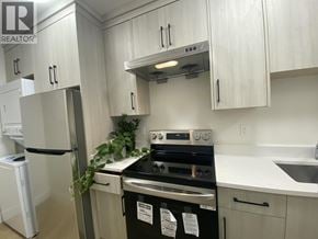 Burnaby apartment for rent - A kitchen with white cabinets and a black stove top oven.